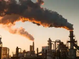 Fumi densi emergono da ciminiere industriali, evidenziando la necessità di monitoraggi ambientali sull'inquinamento atmosferico.