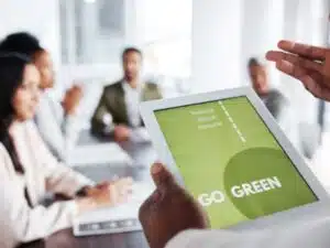 un tablet durante una riunione aziendale mostra il messaggio "GO GREEN" con i principi di riduzione, riutilizzo e riciclo, pilastri di un sistema di gestione ambientale aziendale.